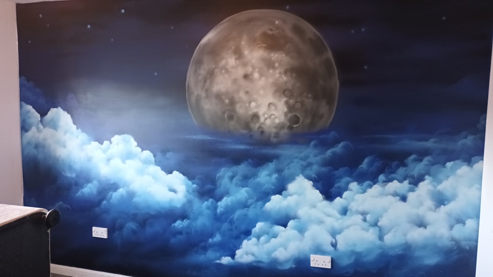 A children bedroom wall mural depicting a large, detailed moon hovering over deep blue, luminous clouds in a starry night sky.