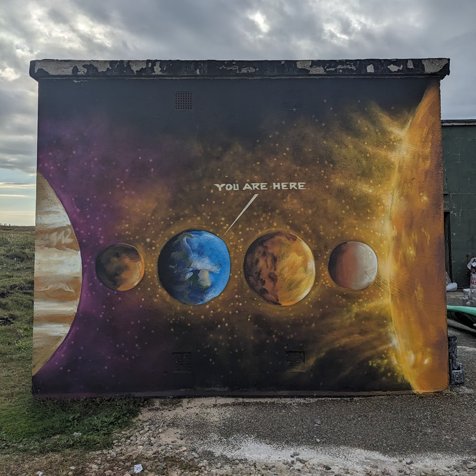 Mural on a former radar and communications station on Gallan Head (Isle of Lewis) depicting the inner solar system with Earth clearly marked by a "YOU ARE HERE" pointer against a starry background next to a massive sun.