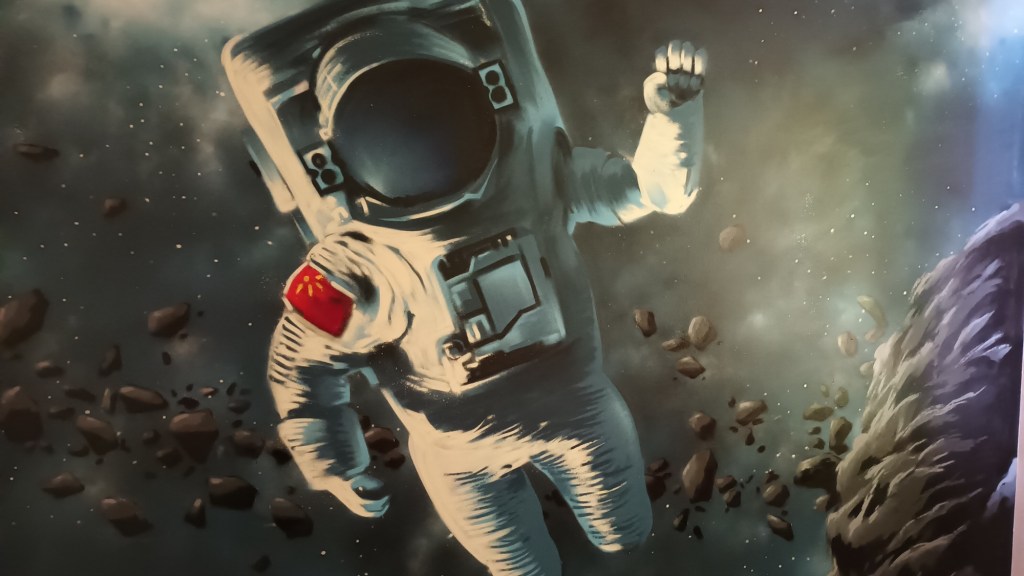 Painting of a Chinese astronaut in a white spacesuit floating amidst asteroids and a starry nebula.